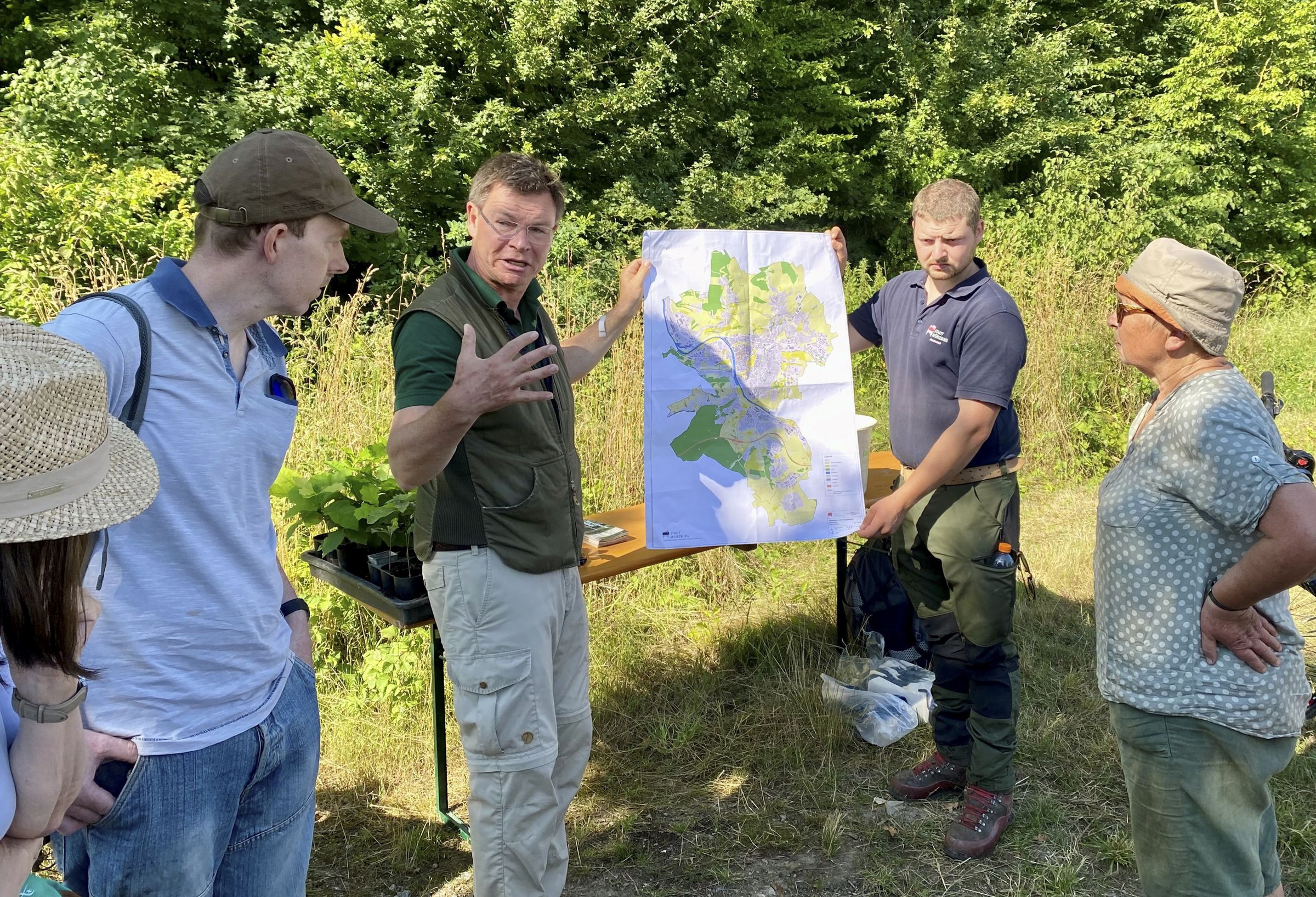 Stadtförster Karl-Georg Schönmüller (Mitte) erklärte den freiwilligen Helferinnen und Helfern, warum der neu angelegte Wald am Standort in Heidingsfeld so wertvoll ist (Bild: Andreas Jungbauer) Stadtförster Karl-Georg Schönmüller (Mitte) erklärte den freiwilligen Helferinnen und Helfern, warum der neu angelegte Wald am Standort in Heidingsfeld so wertvoll ist (Bild: Andreas Jungbauer)